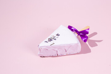 Portioned cheesecake on a stick on a pink background