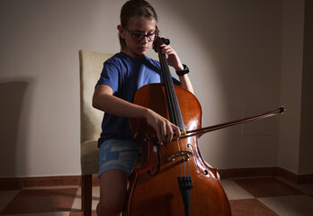 Young Girl Playing Cello in a Warmly Lit Room Demonstrating Musical Talent
