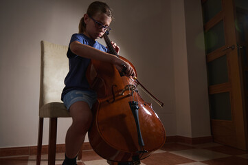 Young Girl Practicing the Cello in a Cozy Room Setting During the Evening