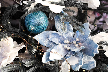 Decorative blue flowers and ornaments on a festive Christmas tree with white accents
