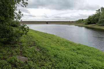 A partially filled reservoir in Yorkshire with green vegetation on the exposed banks, highlighting...