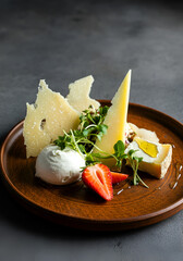  slightly top-down shot of an artisanal cheese plate featuring hard cheese shards, soft creamy cheese with a drizzle of honey, fresh strawberry slices, and microgreens on a handcrafted brown ceramic p