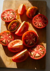 Vibrant heirloom tomato slices on a wooden cutting board, glistening under warm sunlight. 