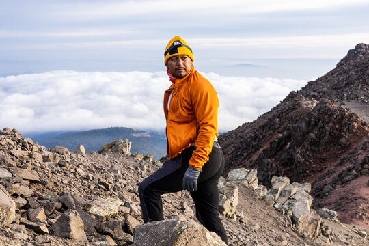 Hiker on Rocky Mountain Trail Amidst Scenic Clouds