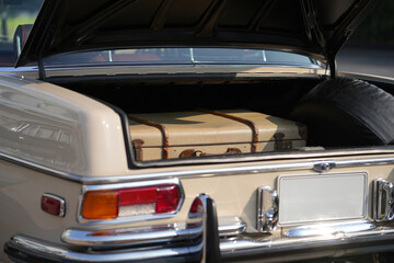 A vintage car trunk opened to reveal a vintage suitcase, evoking the sense of travel and elegance....