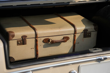 A vintage car trunk opened to reveal a vintage suitcase, evoking the sense of travel and elegance....