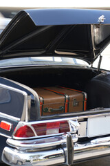 A vintage car trunk opened to reveal a vintage suitcase, evoking the sense of travel and elegance....