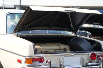 A vintage car trunk opened to reveal a vintage suitcase, evoking the sense of travel and elegance....
