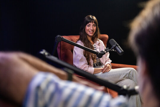 Cozy podcast studio with hosts and microphones