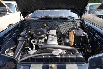 The engine and battery compartment of a classic car, with its detailed mechanical and electrical...