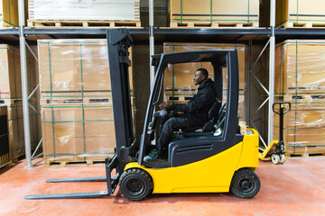 Worker operating forklift in solar panel warehouse