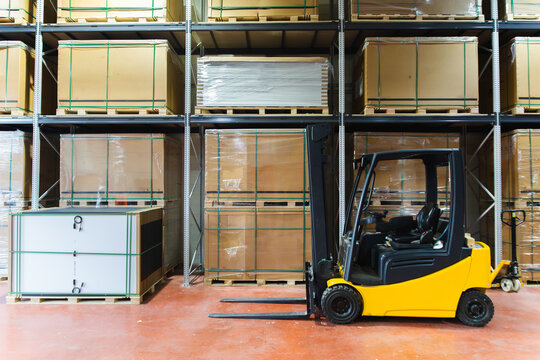 Forklift in a solar panel warehouse with stacked boxes and pallets