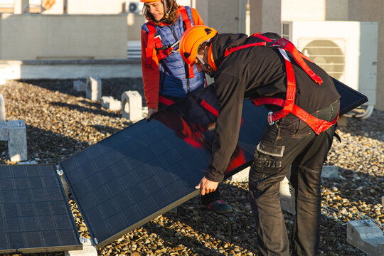Technicians installing rooftop solar panels safely