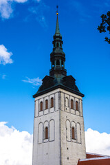 St. Nicholas Church (Niguliste kirik) tower in Tallinn Old Town, Estonia, featuring historic white stone walls, Gothic architecture and tall green copper spire.