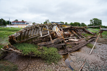 Abandoned Boats – Coastal Landscape. A collection of weathered sailboats rests on a muddy tidal...