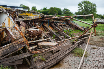 Abandoned Boats – Coastal Landscape. A collection of weathered sailboats rests on a muddy tidal...
