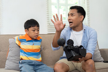 Father and Son Interaction. Dad explaining a vintage camera to his curious son on the couch.