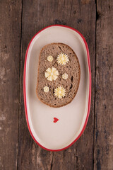 Butter in the form of flowers on a piece of bread on a plate on a wooden table.