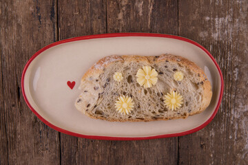 Butter in the form of flowers on a piece of bread on a plate on a wooden table.