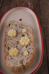 Butter in the form of flowers on a piece of bread on a plate on a wooden table.