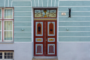 Elegant double wooden door with gold accents, intricate patterns, and floral stained glass, located...