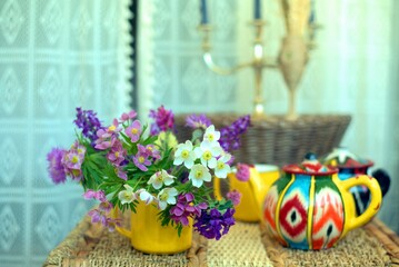 Bouquet of wild flowers with pink anemones and yellow teapot