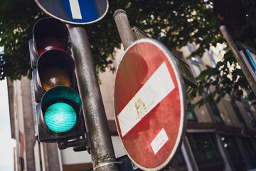 Green traffic light shining near no entry sign in urban setting