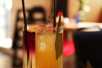Delicious lemonades in glass cups. Refreshing drinks in a cafe or restaurant. Lavender and citrus lemonade close-up. Glass cups with delicious bright drinks. Cocktails with straws. Drinks with ice
