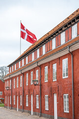 The historic barracks of Kastellet feature striking red buildings and a prominent Danish flag....