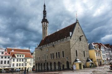 Obraz premium Tallinn Town Hall with medieval Gothic architecture and high spire in Old Town square, Estonia, captured with dramatic cloudy sky.