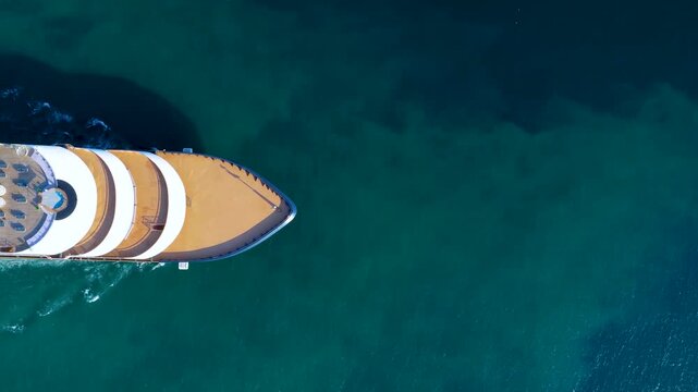 High aerial top down view of a passing by luxury cruise ship or super yacht sailing over blue ocean