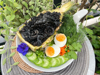 Black squid ink risotto with squid and boiled egg in the pineapple