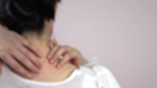 Blurred, closeup shot of a young woman scratching her neck and back. Defocus shot of itchy body with skin problem. 4K