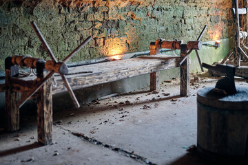 Wooden medieval torture rack with ropes and cranks in stone walled dungeon, illuminated by dim...