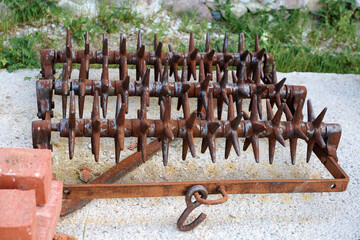 Close up of rusty spiked harrow agricultural farm implement used for surface tillage. Harrow...