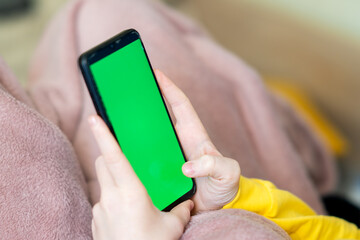 Child's hands holding green screen phone