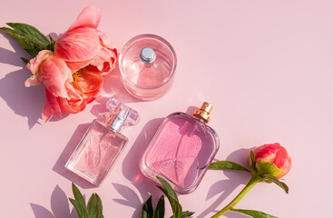 Top view of perfume bottles and flowers on pink background