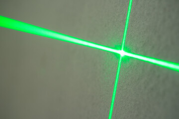 The abstract image of green laser line from the leveling device shows the crossing lines in shallow dept of field
