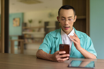 portrait of a young non binary gay man doctor using phone