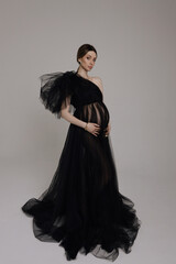 beautiful pregnant woman with dark hair in luxurious evening tulle black dress