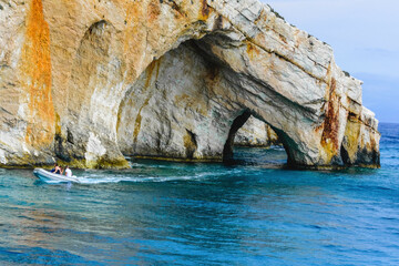 Tourist boat near the famous rocky arch of the Blue Caves in Zakynthos, Greece, showcasing clear turquoise waters and striking sea-carved cliffs.