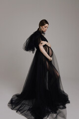 beautiful pregnant woman with dark hair in luxurious evening tulle black dress