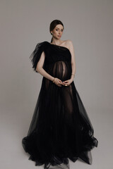 beautiful pregnant woman with dark hair in luxurious evening tulle black dress