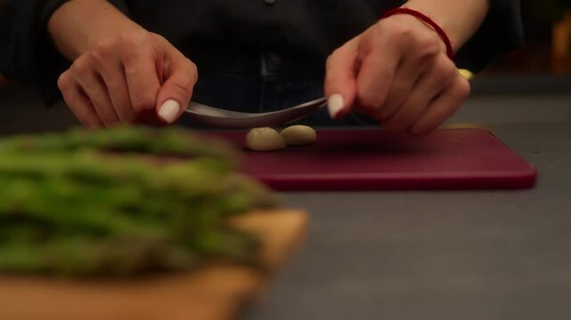 Chef peeling garlic cloves with garlic press on cutting board