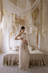 beautiful pregnant slavic woman with dark hair in elegant dress posing in elegant bedroom