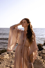 beautiful woman with dark hair in elegant beach clothes posing on the beach
