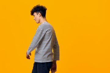 young man in striped long sleeve shirt posing sideways with serious expression against vibrant...
