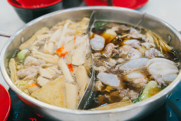 Delicious Asian Hot Pot with Seafood and Vegetables in a Metal Pot on a Dining Table