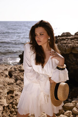 beautiful woman with dark hair in elegant dress posing on the beach