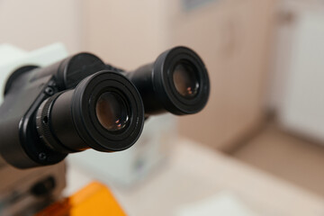 Black medical microscope in clinical office setting with diagnostic equipment